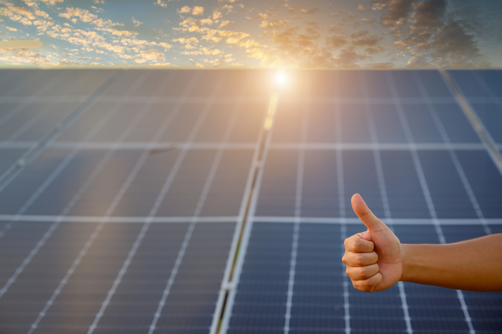 Energias renováveis: placa solar fotovoltaíca com uma mão de homem afirmando.